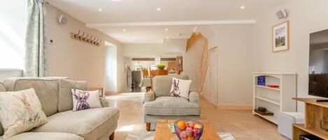 A modern living room with a sofa, armchair, coffee table, and a television.