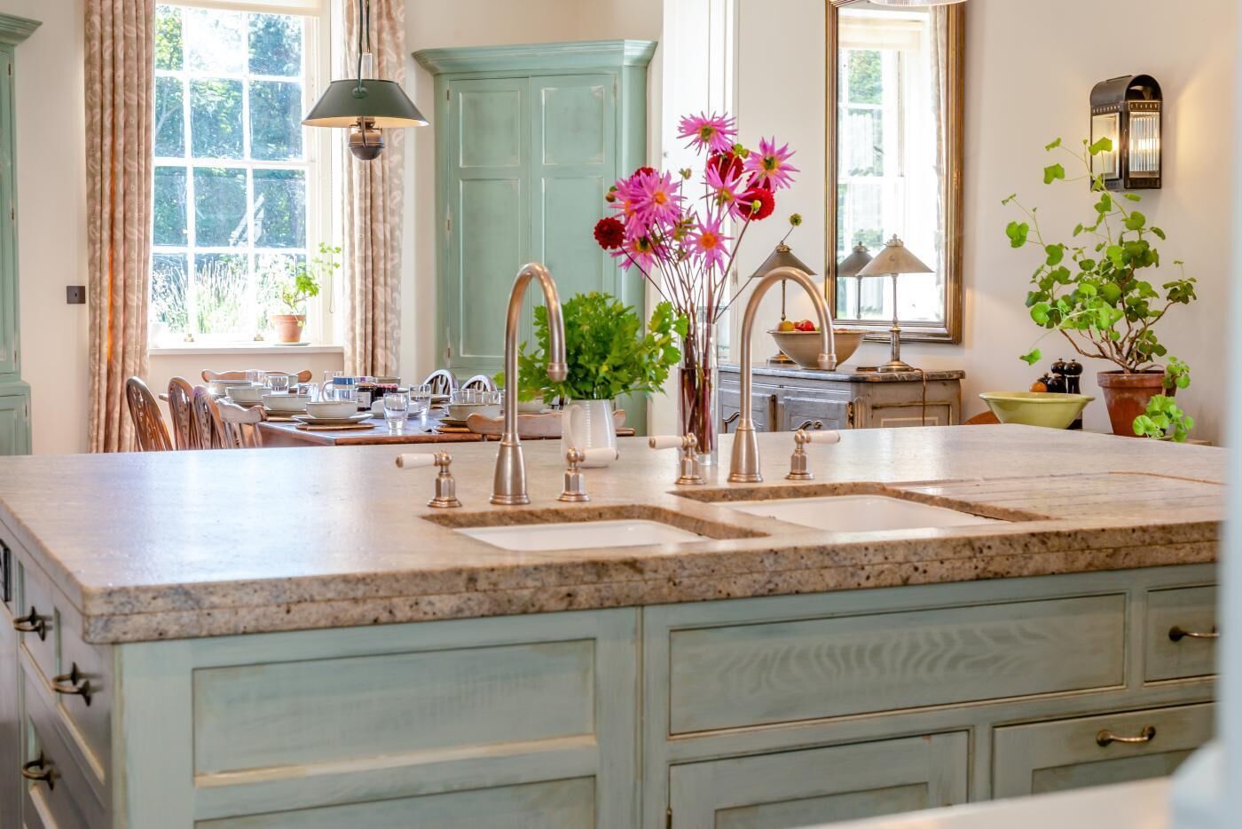 A kitchen with a granite countertop, two sinks, and a light blue cabinet.
