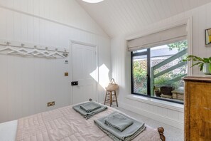 Une chambre à coucher avec un lit, une fenêtre donnant sur un beau paysage, une commode en bois et une porte.