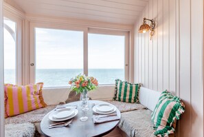 Un coin repas avec une table dressée pour deux personnes, donnant sur la mer.