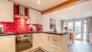 Una cocina moderna con armarios blancos, un backsplash rojo y una isla grande con fregadero.