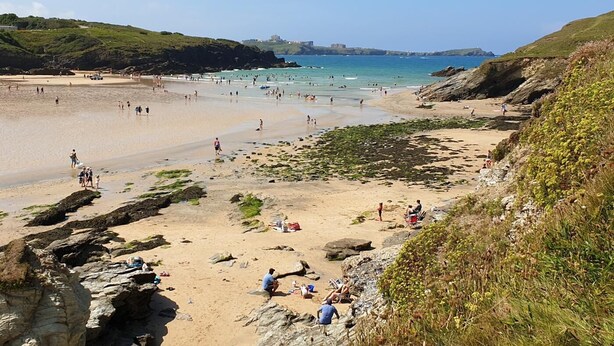 A beach with people, rocky areas, and a distant view of a town. - 1 Bed in Tresillian (oc-t32988) (Tresillian)
