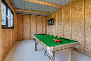 A pool table with balls, a dartboard, and a window in a room with wooden walls. - 4 Bed in Brecon (oc-m32973) (Brecon)