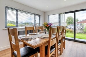 Un coin repas avec une table en bois, des chaises et un vase de fleurs.