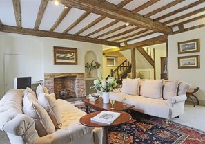 A cozy living room with a fireplace, a sofa, a coffee table, and a patterned rug.