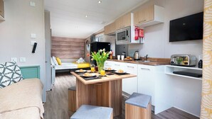 Eine kompakte Küche mit Kochinsel, einer Mikrowelle, einem Toaster und einem flachbildschirmigen Fernseher an der Wand.