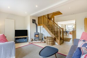 Ein Wohnzimmer mit Fernseher, Kamin, Treppe und Essbereich.