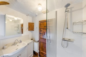 A bathroom with a glass shower enclosure, a wooden door, a white sink, and a mirror. - 2 Bed in Llandefalle (oc-n32991) (Llandefalle)