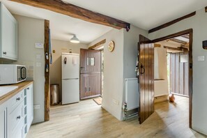 Une cuisine avec des poutres en bois, un réfrigérateur, un four à micro-ondes et une porte en bois.