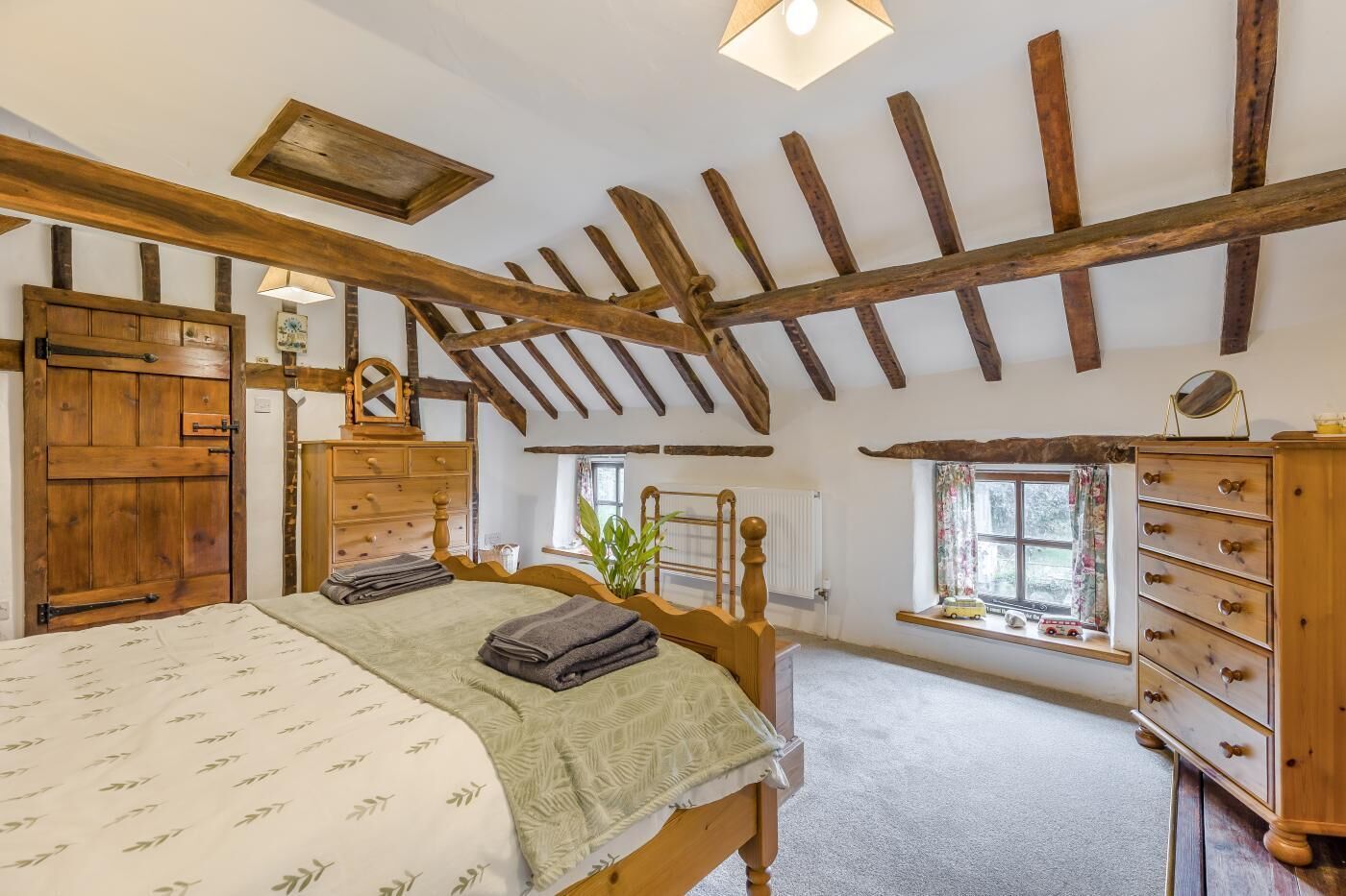 Une chambre à coucher avec un lit, une commode en bois et une fenêtre donnant sur un beau paysage.