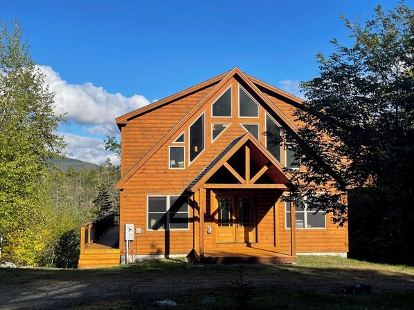A wooden cabin with a gabled roof, large windows, and a front porch.