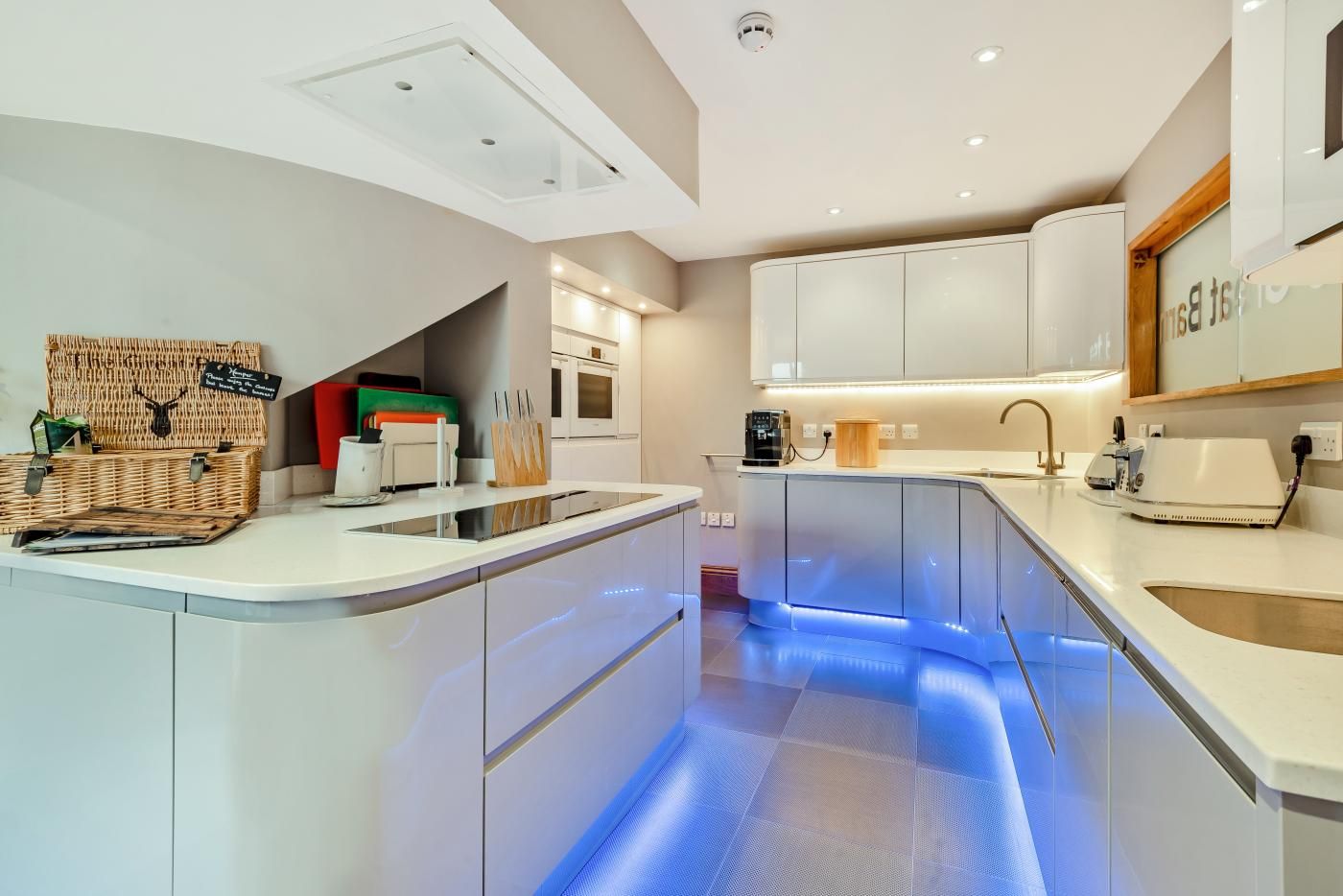 A modern kitchen with a central island, built-in appliances, and under-cabinet lighting.