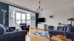 Ein modernes Wohnzimmer mit großem Fenster, Kamin und Flachbildfernseher.