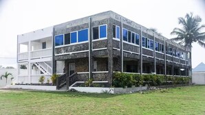 A two-story building with a stone facade, multiple windows, and a balcony. - Lagoona Ocean Suites Monrovia Thinker’s Village (Mills Center)