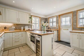 Eine moderne Küche mit weißen Schränken, einem Backofen, einem Spülbecken und einem Fenster mit Jalousien.