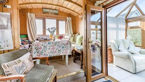 A cozy wooden cabin interior with a dining table, chairs, and a large window. - 2 Bed in Snettisham (oc-e32982) (Snettisham)