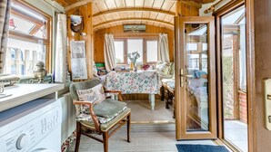 A cozy room with a wooden ceiling, a dining table with floral tablecloth, a wooden chair, and a window with curtains. - 2 Bed in Snettisham (oc-e32982) (Snettisham)