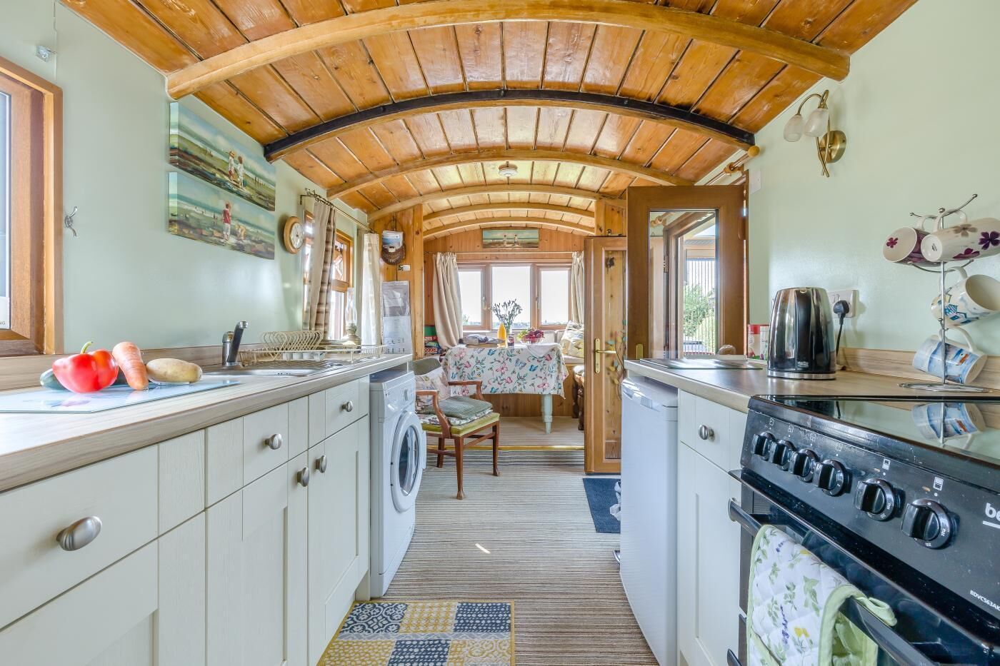 A compact kitchen with a washing machine, a stove, and a dining area with a table and chairs.