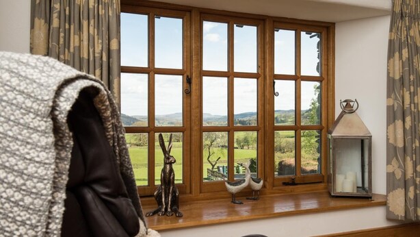 A room with a large window, a wooden floor, and a black leather chair. - 3 Bed in Outgate (oc-gl018) (Outgate)