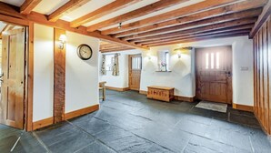 A spacious hallway with stone flooring, wooden beams, a clock, and a bench. - 3 Bed in Outgate (oc-gl018) (Outgate)