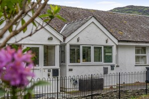 A two-story house with a white exterior, grey roof, and a fenced yard. - 2 Bed in Chapel Stile (oc-gl103) (Chapel Stile)