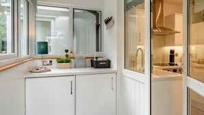 Moderni keittiö, jossa on valkoiset kaapit, ikkuna ja näkymä viereiseen ruokailutilaan.