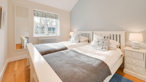 A bedroom with two beds, a window with a view, a radiator, and a bedside table with a lamp. - 2 Bed in Eye (oc-slo) (Wilby)