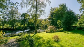 Un parc paisible avec un étang, une végétation luxuriante et une petite cascade.