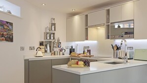 A modern kitchen with an island, built-in appliances, and a breakfast bar. - 2 Bed in Southwold (oc-wtp) (Southwold)