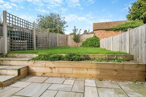 A backyard with a wooden fence, a grassy lawn, and a raised garden bed. - 3 Bed in Little Walsingham (oc-1229) (Little Walsingham)