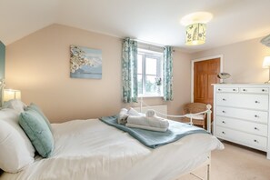 A bedroom with a bed, a dresser, a window with curtains, a painting on the wall, and a lamp. - 3 Bed in Little Walsingham (oc-1229) (Little Walsingham)