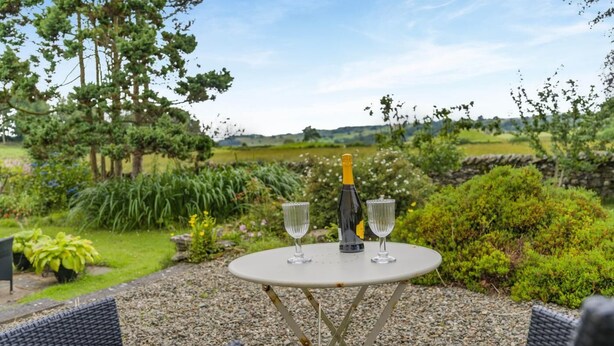 An outdoor seating area with a table, two chairs, a bottle of champagne, and two glasses. - 1 Bed in Crook (oc-gl077) (Crook)