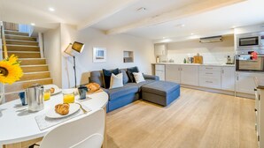 A modern living space with a dining area, a sofa, a kitchen with appliances, and a staircase. - 1 Bed in Crook (oc-gl077) (Crook)