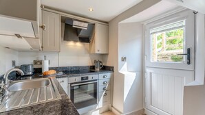 A modern kitchen with a built-in oven, a sink, and a window with a view of greenery.