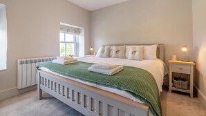 A bedroom with a bed, bedside table, lamp, and a window.