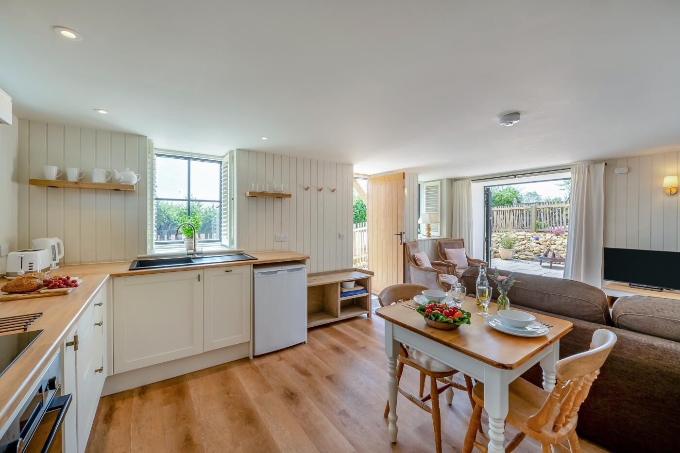 A modern kitchen with white cabinets, a wooden countertop, and a built-in dishwasher.