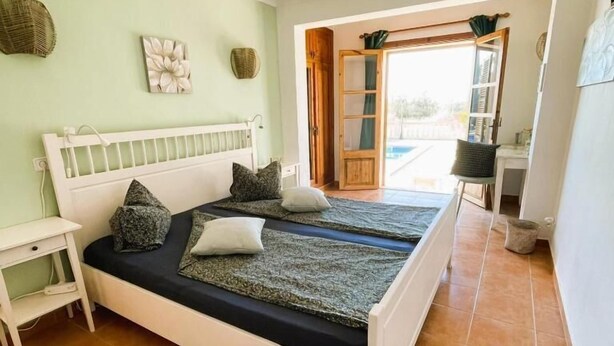 A bedroom with a bed, a nightstand, a window, and a view of the outside. - Agroturismo S'Hort de Can Carrio (Ses Salines)