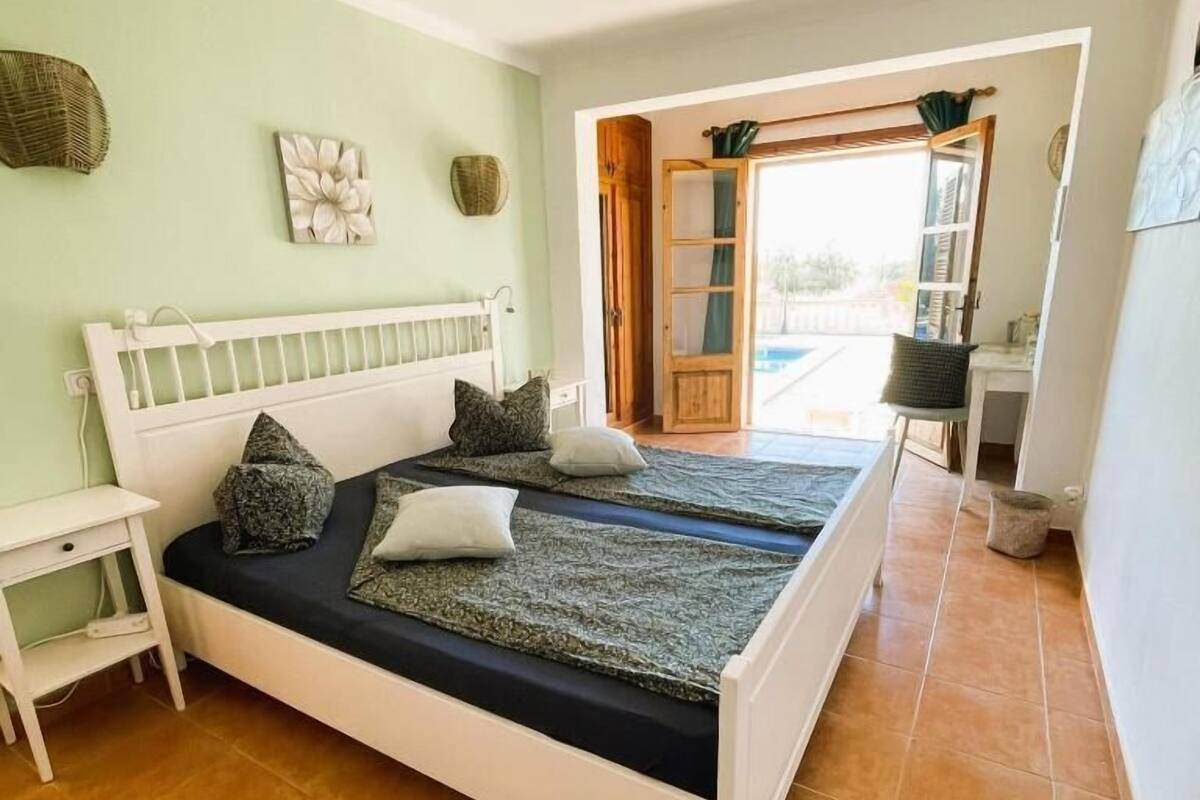 Quarto com cama, mesa de cabeceira, janela e vista para o exterior.