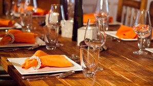 A dining table set with plates, cutlery, and glasses, with orange napkins and a decorative centerpiece. - Agroturismo S'Hort de Can Carrio (Ses Salines)