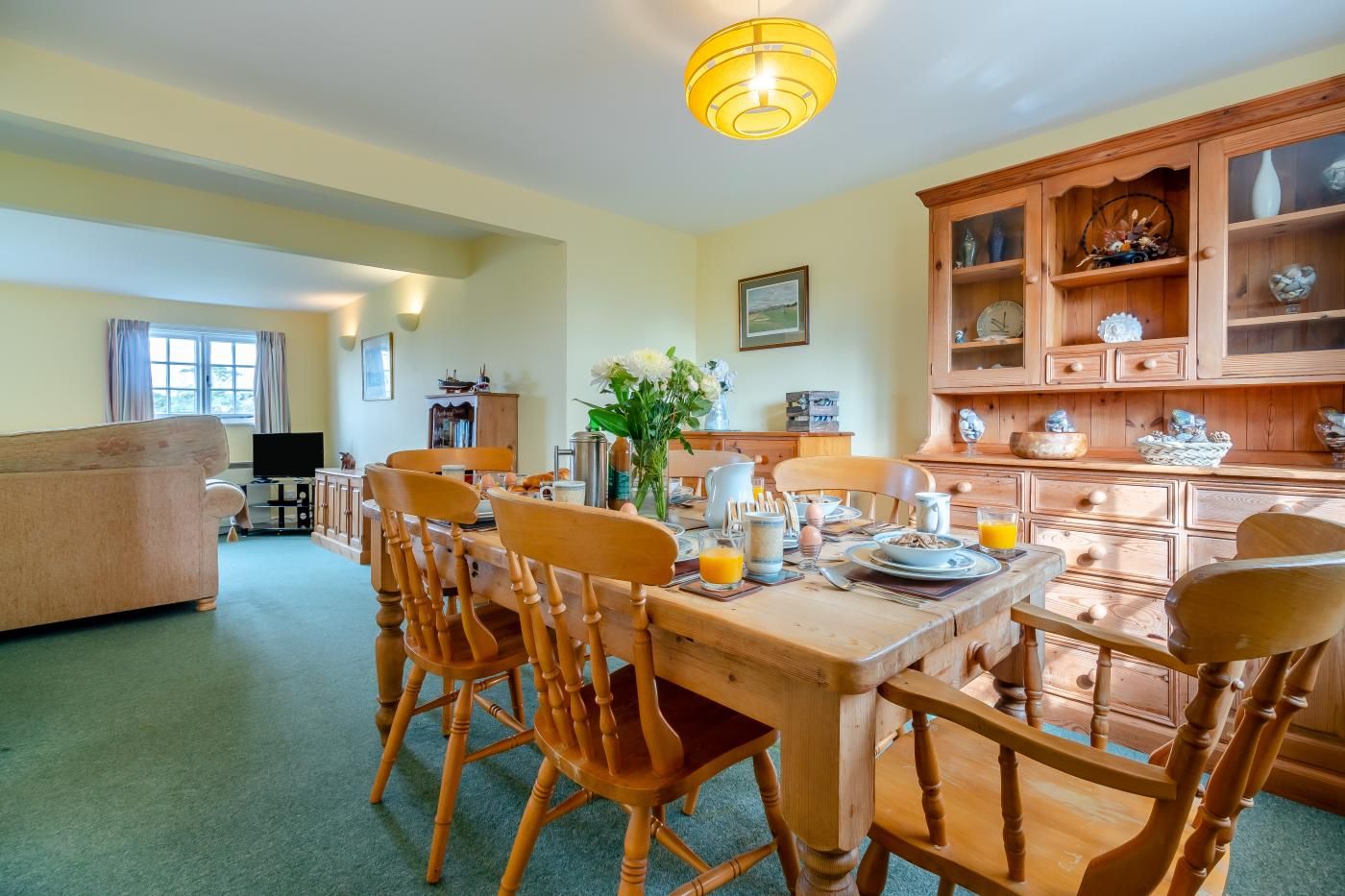 A dining area with a wooden table set for breakfast, surrounded by chairs.