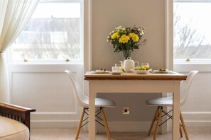 A dining table with chairs, a vase of flowers, a teapot, and a fruit bowl. - 1 Bed in Bath (oc-bhr12) (Bath)