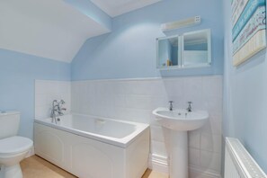 Un baño con bañera, lavamanos e inodoro.