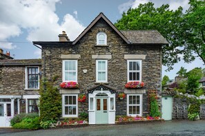 A stone building with a gabled roof, multiple windows, and flower boxes. - 4 Bed in Windermere (oc-gl130) (Windermere)