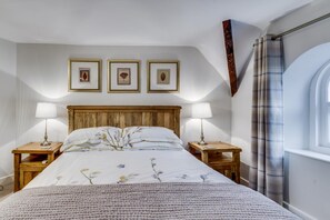 A bedroom with a wooden headboard, two bedside tables with lamps, a large bed with floral bedding, and three framed pictures on the wall. - 4 Bed in Windermere (oc-gl130) (Windermere)