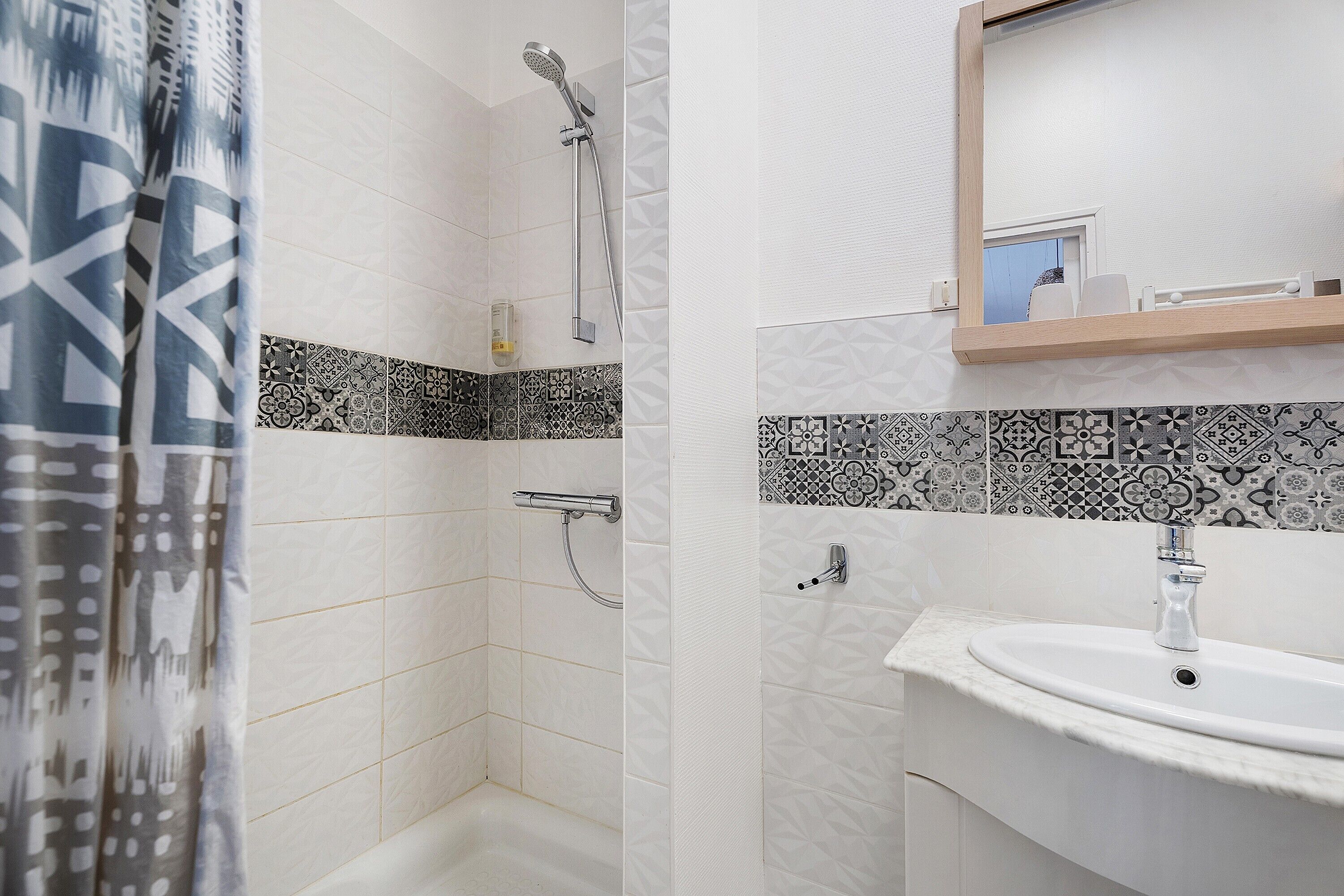 Ein Badezimmer mit Dusche, Waschbecken und Spiegel.