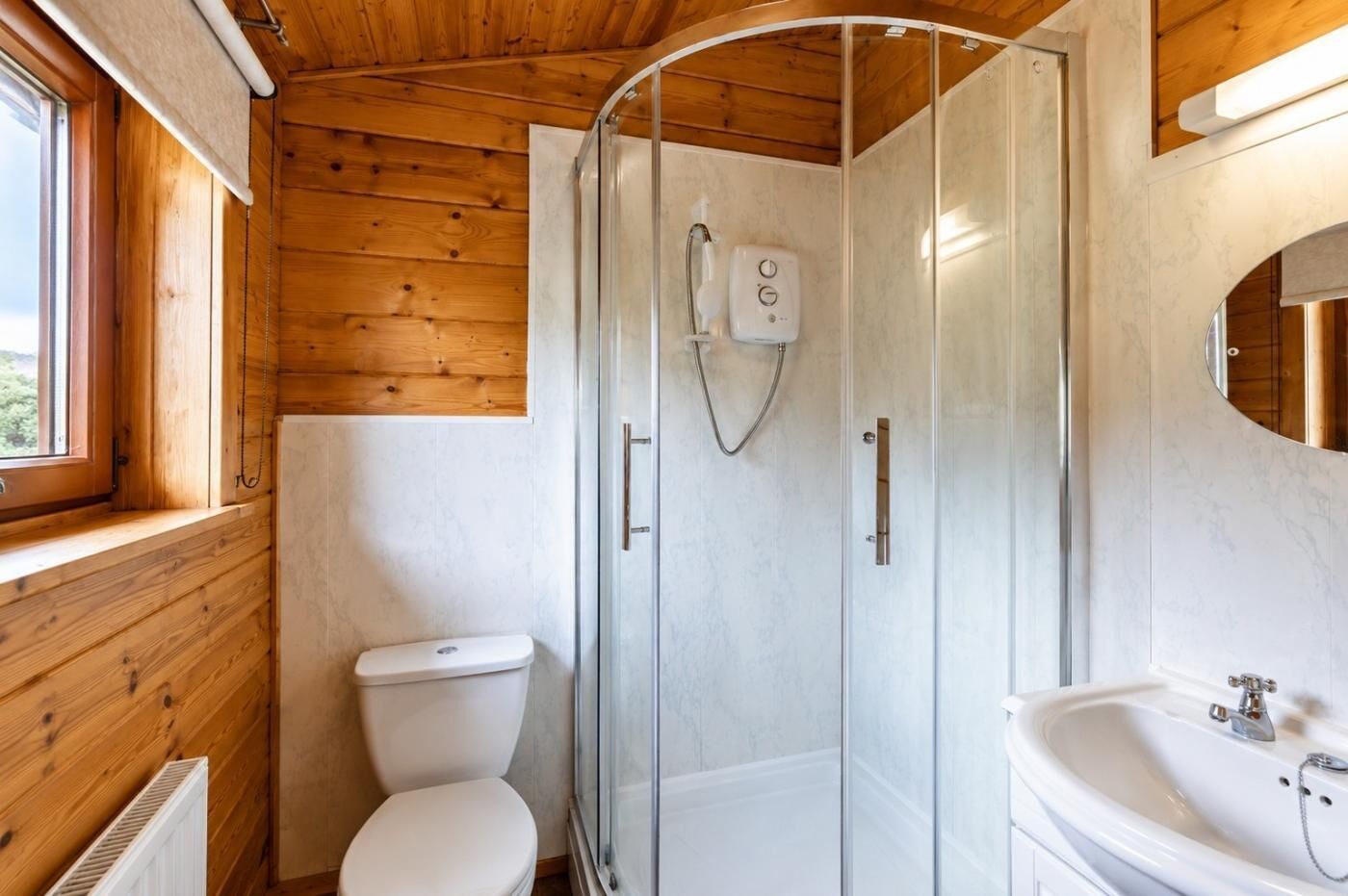 Une petite salle de bain avec une douche à parois de verre, des toilettes blanches et un lavabo avec un miroir.