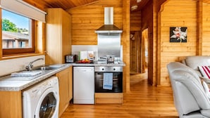 Una cocina compacta con paredes de madera, lavadora, lavavajillas y estufa.