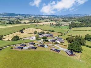 An aerial view of a rural farm with barns, solar panels, and fields. - 1 Bed in Llandinam (oc-t33065) (Llandinam)