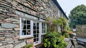 Une petite maison en pierre avec une pancarte indiquant « Mill Race Cottage ».