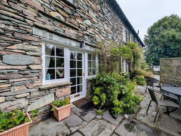 A stone cottage with a sign reading "Mill Race Cottage". - 2 Bed in Elterwater (oc-gl053) (Chapel Stile)